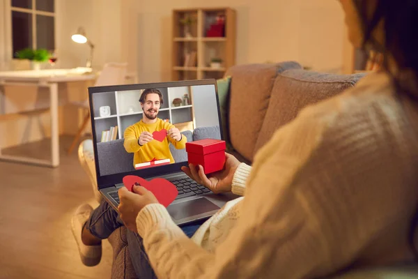 Genç, sevgi dolu mutlu çift çevrimiçi video görüşmesi sırasında birbirlerine dekoratif kırmızı kalp ve hediye gösteriyorlar. — Stok fotoğraf