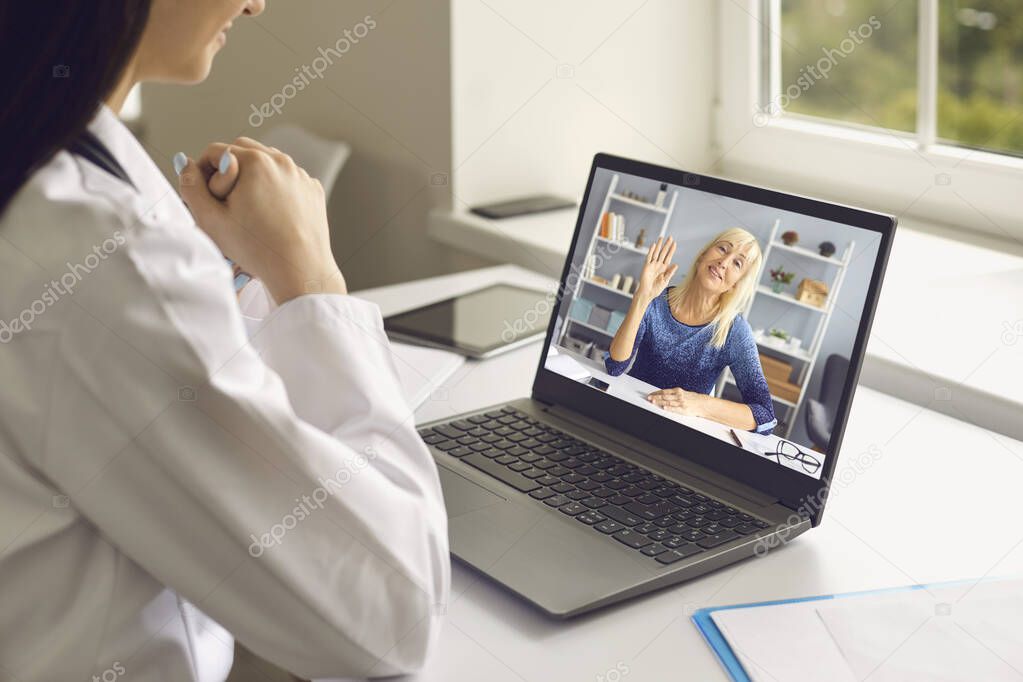 Smiling middle aged woman patient greeting woman doctor online during distant meeting videocall