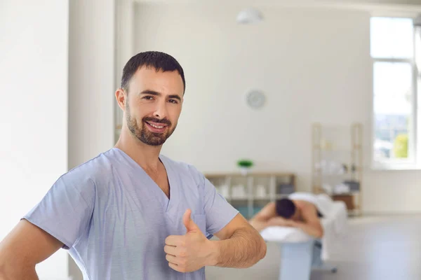 Улыбающийся доктор хиропрактик или массажист показывает большой палец вверх знак — стоковое фото