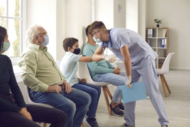 Grip ya da Covid-19 aşısı olmak için sırada bekleyen tıbbi maske takan çeşitli insanlar.