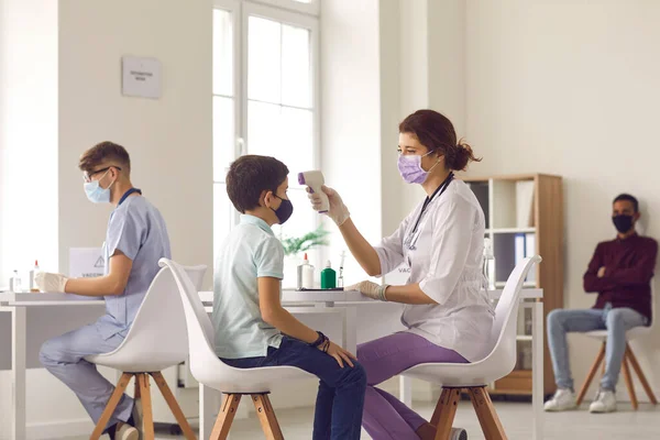 Nurse using non-contact infrared thermometer to measure little boys temperature — Stock Photo, Image