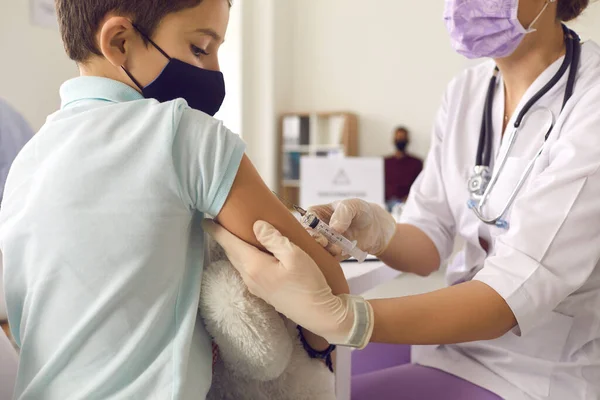 Dzielny mały pacjent w masce do twarzy, patrzący na igłę podczas szczepienia przeciw grypie. — Zdjęcie stockowe