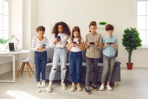 Niños con teléfonos jugando juegos, usando aplicaciones de aprendizaje, mensajes de texto o blogueando e ignorando la vida real —  Fotos de Stock