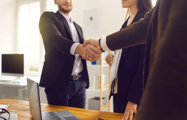 İş ortakları, modern ofiste yapılan başarılı müzakere sonrasında el sıkışıyor.