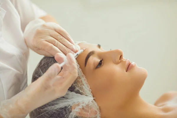 Woman recieving injection of anti-aging botox filler to forehead skin from professional cosmetologist — Stock Photo, Image