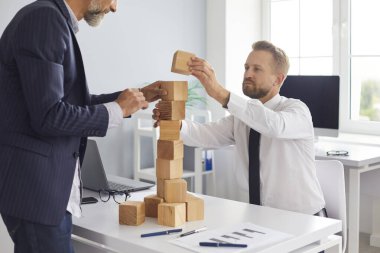 Baba ve oğul, aile işlerini güçlendirme metaforu olarak ofis masasına oyuncak kulesi inşa ediyorlar.