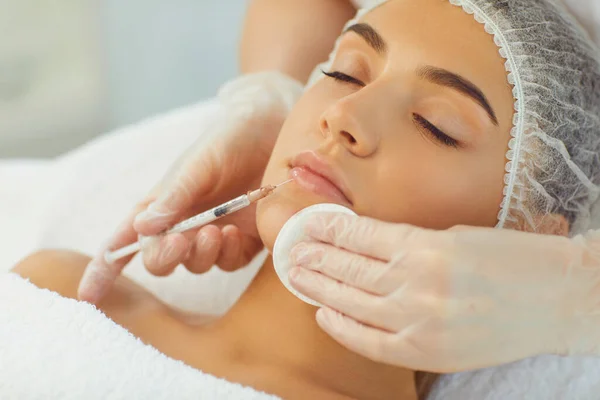 Mani di cosmetologo con siringa e batuffolo di cotone che fanno l'iniezione di riempimento botox nelle labbra femminili — Foto Stock