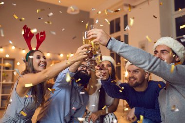Dekoratif şapkalı bir grup pozitif arkadaş Noel 'i parti sırasında şampanyayla kutluyorlar.