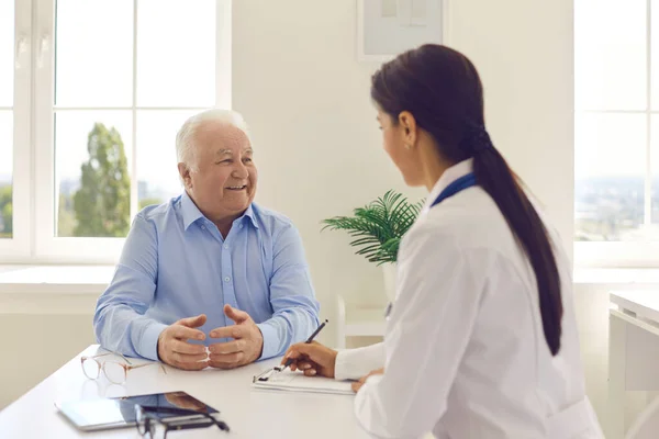 Smiling senior man patient describing complaints to woman doctor