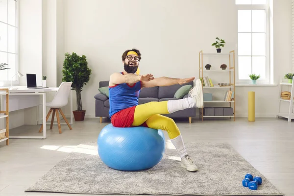 행복 한 젊은이가 집에서 운동 경기를 하면서 적합 한 공 위에 앉아서 운동을 하고 있다 — 스톡 사진