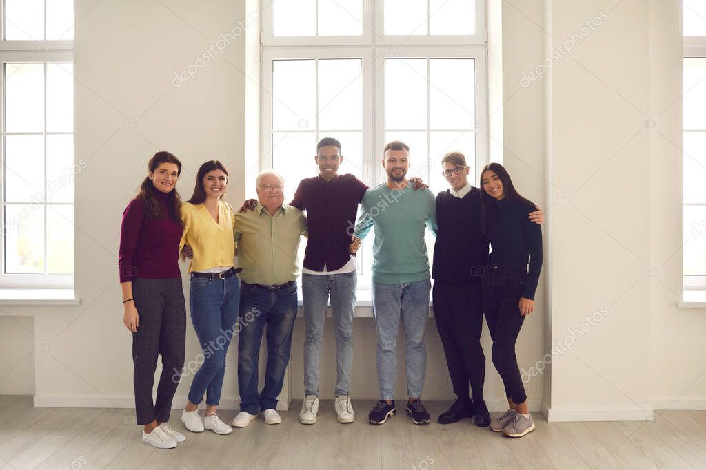 Group portrait by the window of happy positive diverse people of different genders, races and ages.