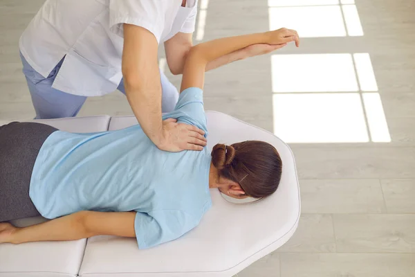 Dłonie lekarza masażysty osteopaty mocujące leżących pacjentów z plecami i ramieniem — Zdjęcie stockowe
