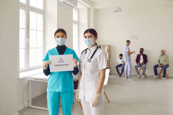 Jonge artsen in medische gezichtsmaskers bevorderen vaccinatiecampagne die levens redt — Stockfoto