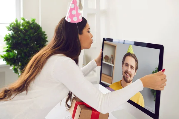 Genç bir kadın sevgilisiyle online doğum günü partisi veriyor ve bilgisayar ekranını öpüyor. — Stok fotoğraf