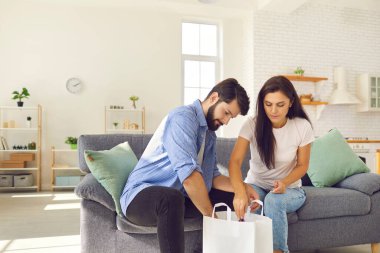 Genç bir adam ve bir kadın, teslimat servisi tarafından teslim edilen beyaz bir poşet paketini boşaltıyorlar..