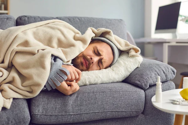 Közelkép a beteg ember influenzás, láz és fejfájás alszik kockás kanapén. — Stock Fotó