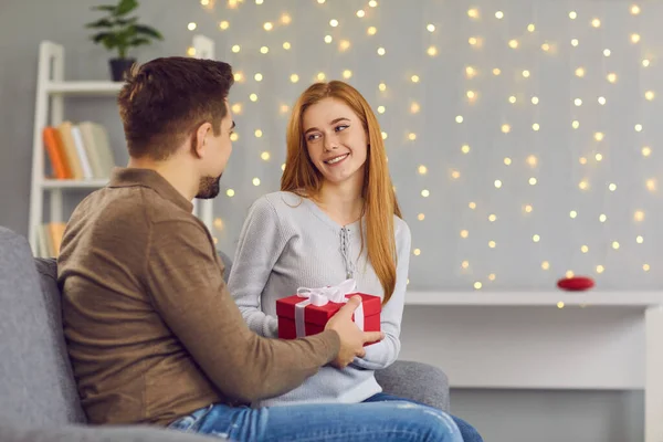 Mladá usměvavá žena přítelkyně sedí a dostat dárek box s stuhou od milujícího muže — Stock fotografie