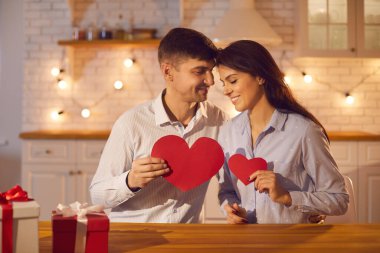 Aşık romantik çift ellerinde kağıt kırmızı kalpler tutuyorlar. Bu onların aşkının sembolü..