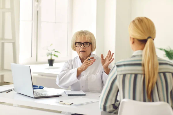 Senior female doctor říká a vysvětluje pacientovi jeho diagnózu během konzultace. — Stock fotografie