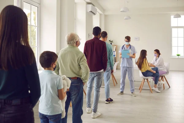 Diverse people lining up waiting for their turn to get shots in modern vaccination center — Stock Photo, Image