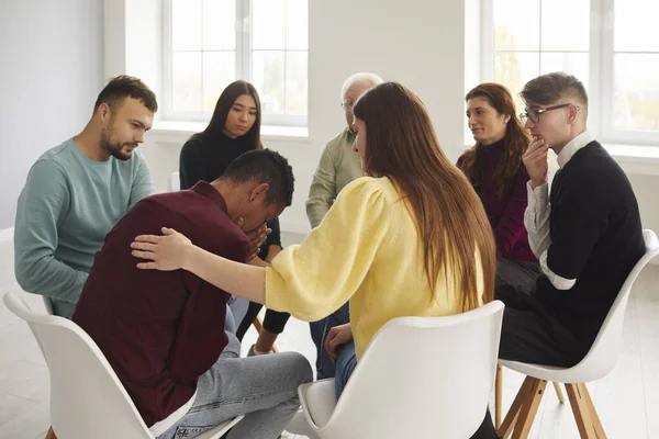 Diverse mensen ondersteunen en troosten huilende jongeman in groepstherapie sessie — Stockfoto