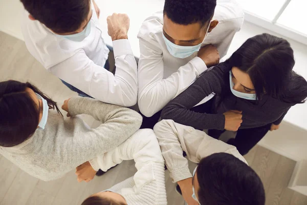 Business people partners wearing medical protective face masks putting elbows together — Stock Photo, Image