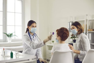 Çocuk sıcaklığını ölçen dost canlısı doktor ile temas olmayan kızılötesi termometre.