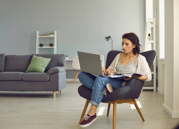 Frau schaut mit Laptop zu und macht sich Notizen während Videocall oder Online-Unterricht — Stockfoto