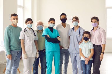 Kendine güvenen doktorlar ve hastalar kameraya bakıyor. Virüsü durdurmak için maske takmanızı istiyorlar.