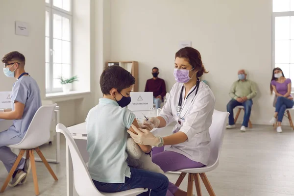 Vorsichtige Krankenschwester mit medizinischer Gesichtsmaske gibt ihrem kleinen Patienten eine Grippeimpfung — Stockfoto