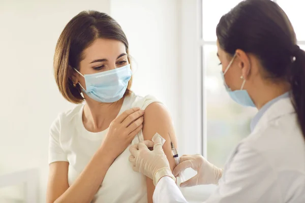 Young patient in a medical face mask getting an antiviral vaccine at the hospital — Stock Photo, Image