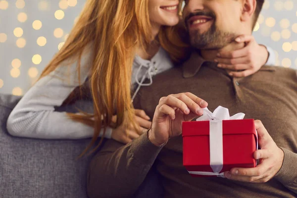 Mujer sonriente abrazando a su novio que abre su regalo de San Valentín o cumpleaños — Foto de Stock