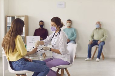 Doktor, Covid-19 antiviral aşıyı vermeden önce hastaya imzalaması için belgeler veriyor..
