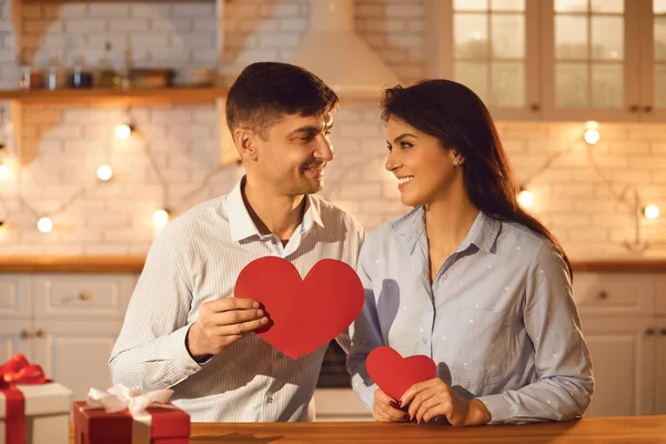 Šťastný mladý pár milenci s červenými srdci v rukou při pohledu na sebe během Valentines den oslav — Stock fotografie