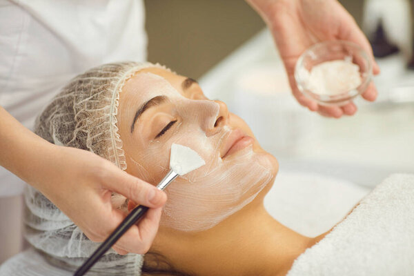 Relaxing womans face getting procedure of applying moisturizing mask with brush