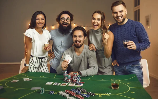 Gruppe junger lächelnder Freunde hat Spaß beim Brettspiel mit Karten und Chips zu Hause — Stockfoto