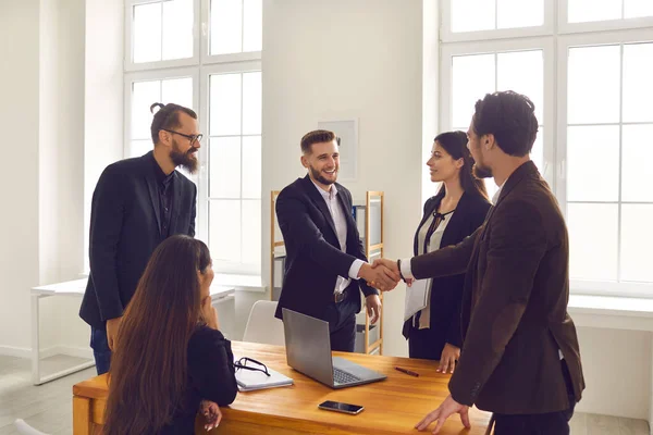 Les jeunes gens d'affaires concluent un accord et se serrent la main après une négociation réussie dans le bureau de l'entreprise — Photo