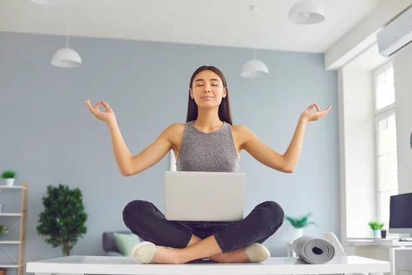 Büroangestellte mit positiver Einstellung sitzt in lockerer Pose am Schreibtisch und meditiert und entspannt — Stockfoto