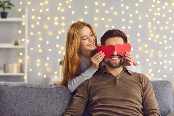 성 발렌티노 축일에 붉은 하트 모양의 카드로 남자 친구의 눈을 가리고 있는 여자 — 스톡 사진