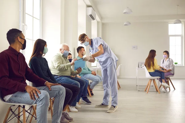 Pessoas diversas esperando na fila no hospital e assinando papéis que o médico dá — Fotografia de Stock