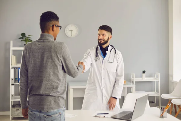 Lächelnder Arzt begrüßt seinen Klienten in seinem Büro in der Klinik oder im Krankenhaus — Stockfoto