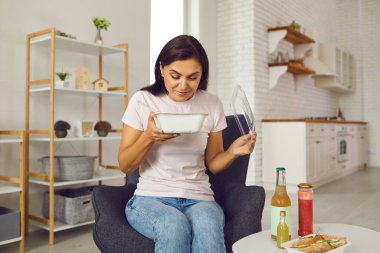 Genç ve mutlu bir kadın taze yemek ile konteynır açıyor ve yemeği kokluyor.