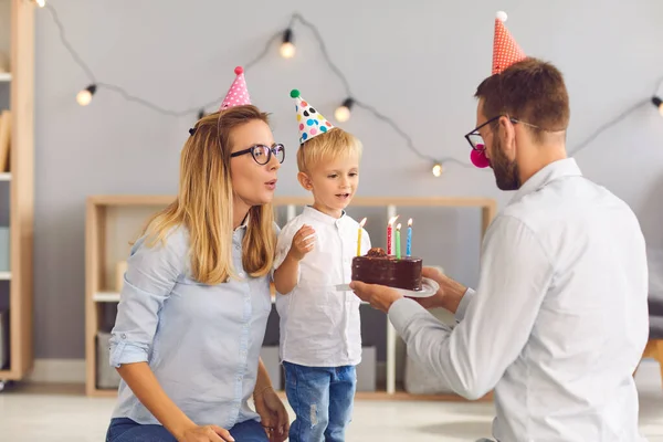 Happy mother and father congratulating little son with birthday with cake