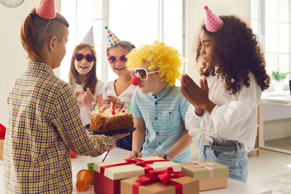 Group of children congratulates their friend on his birthday and gives him gifts and a cake. — Foto de Stock