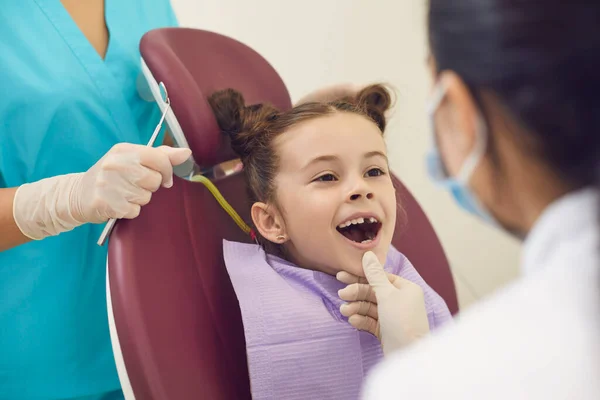 Οδοντίατρος γυναίκα εξετάζει χαμογελαστά κορίτσια δόντια σε ανοιχτό στόμα στην οδοντιατρική κλινική — Φωτογραφία Αρχείου