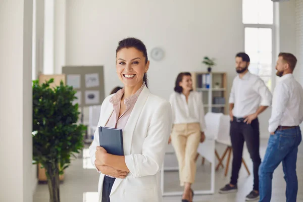 Fröhliche Managerin steht nach Treffen im Büro und lächelt in die Kamera — Stockfoto