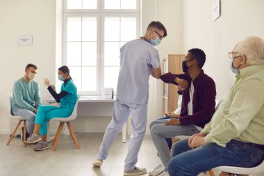 Genç doktor, koronavirüs salgını sırasında Afrikalı bir Amerikan hastasını selamlıyor..