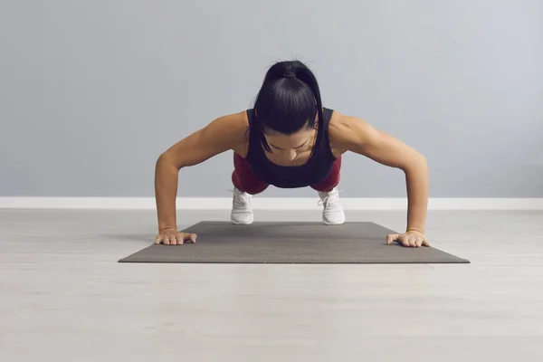 Atletische vrouw doet push-ups om de borstspieren, triceps en schouders op te warmen. — Stockfoto