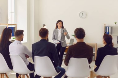 Bir grup ofis çalışanı için sunum ya da eğitim yapan iş kadını konuşmacısı