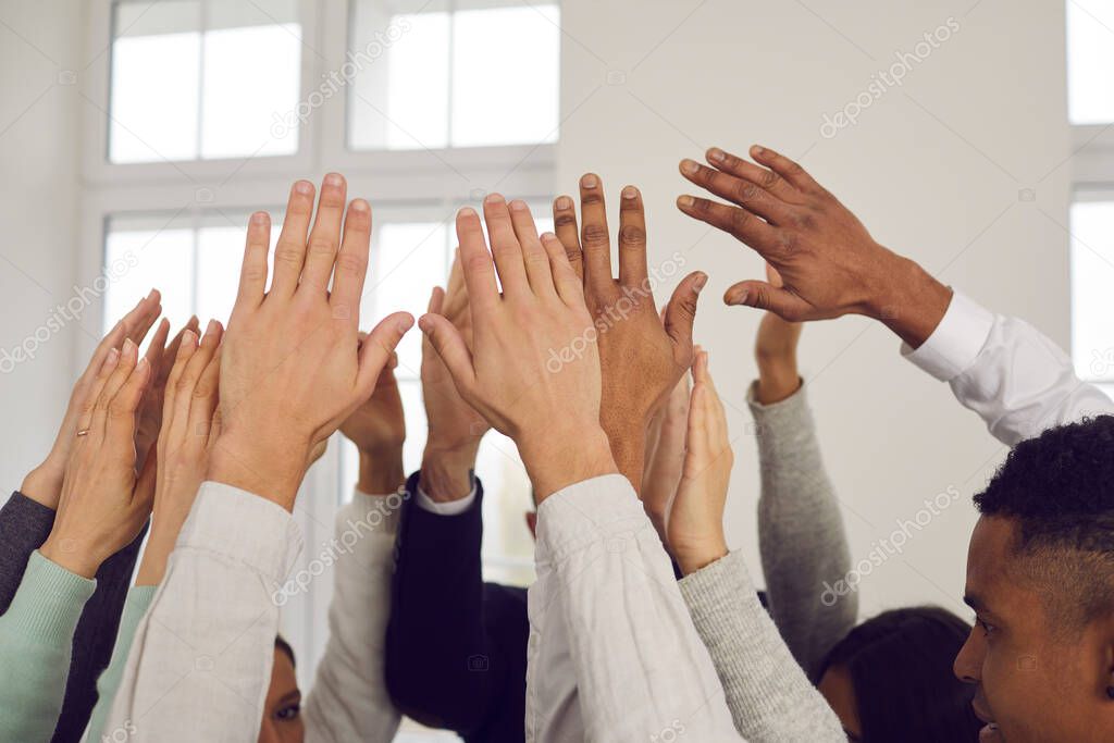 Team of multiracial people raising hands up in the air, showing solidarity, unity and support
